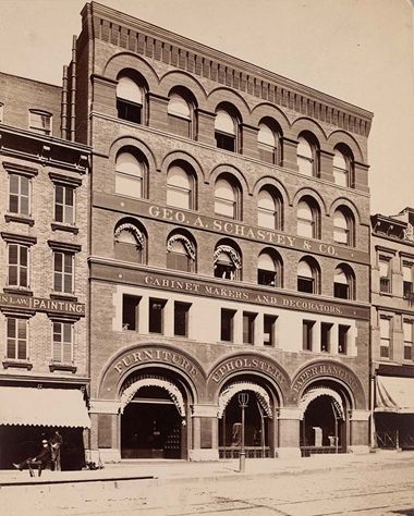 Photograph of George A. Schastey & co. factory and showroom, a 4–5 story building with arched doorways and windows.