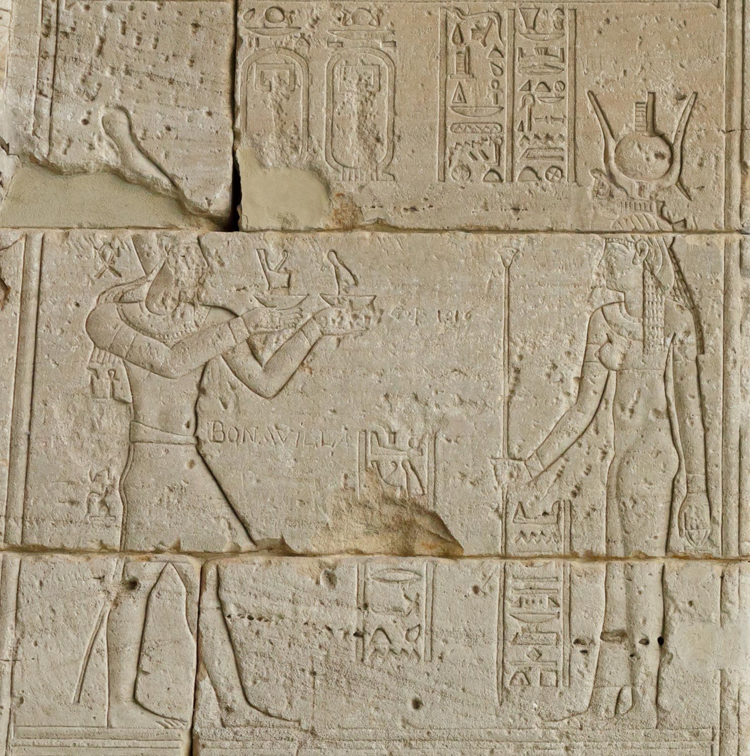 Detail depicting Augustus (left) offering the crowns of Upper and Lower Egypt to the goddess Isis (right). On top of her headdress is a small stepped hieroglyph that depicts a throne and was used to write Isis's name.