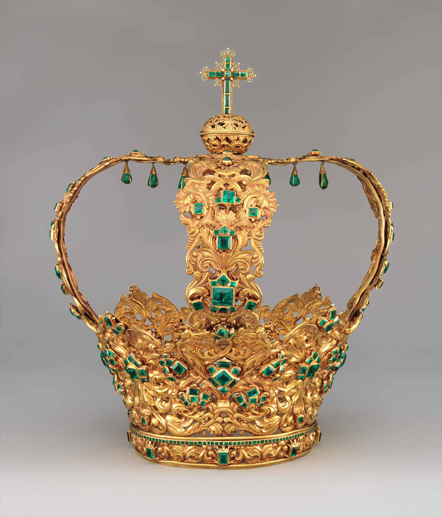 Elaborate golden crown embellished with emeralds with an emerald cross at the top. 