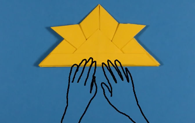A still from a MetKids how to video on folding origami.