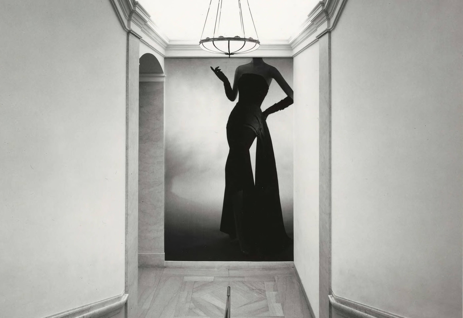 Installation photograph showing a hallway with a floor-to-ceiling photograph of a woman's body wearing a Christian Dior dress 