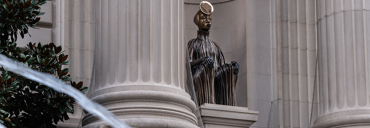 A bronze sculpture is seated in the Met's niches in front of a fountain