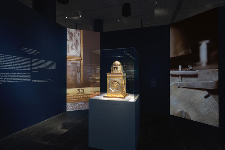 A view of dark blue galleries filled with objects made from silver and gold