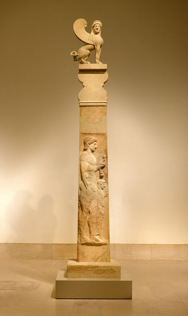 Marble stele from ancient Greece. The shaft depicts a young, athletic man holding a pomegranate and oil flask. His little sister is next to him, holding a flower. The stele is topped with a sphinx.
